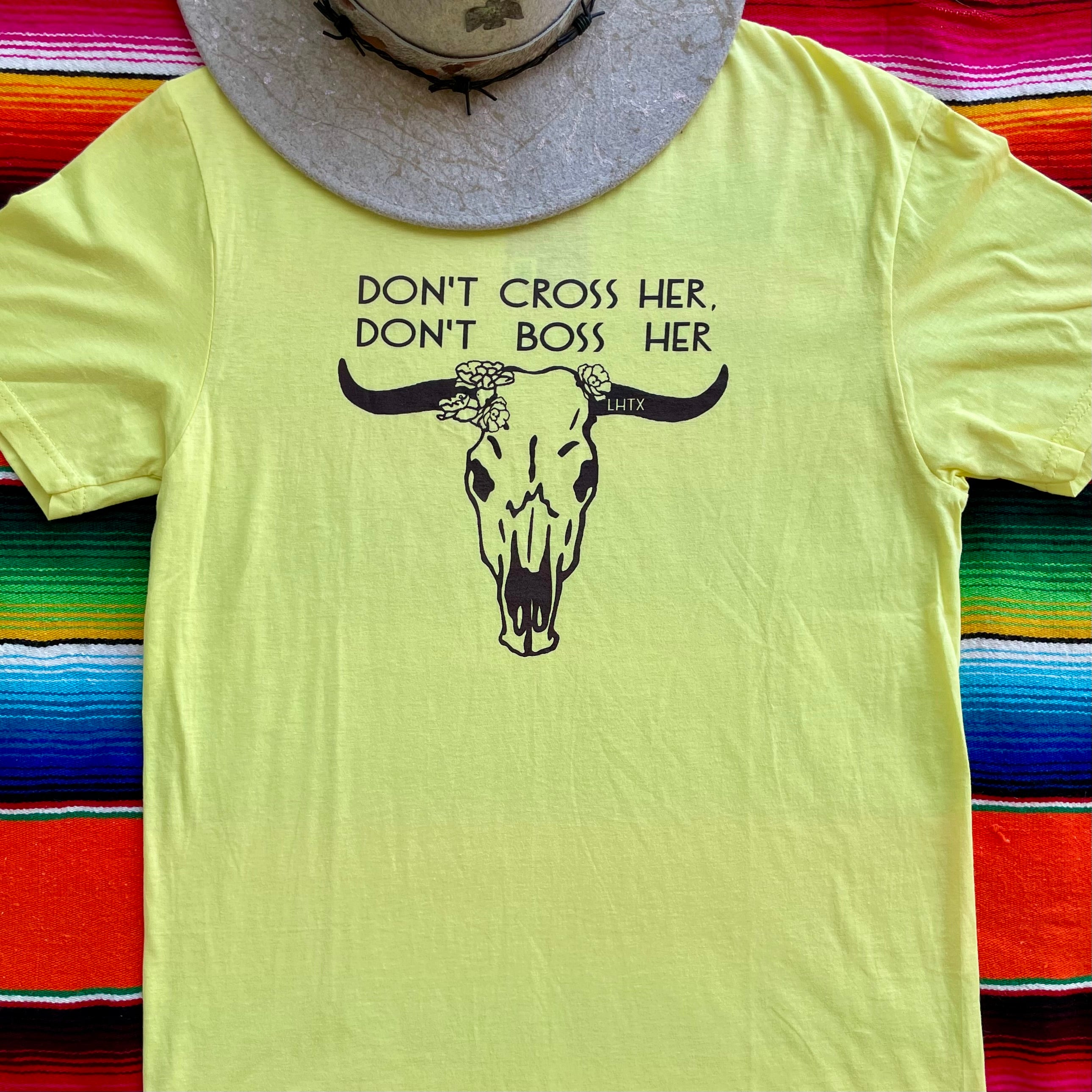 Yellow t-shirt with a bull skull graphic and text on a colorful striped background