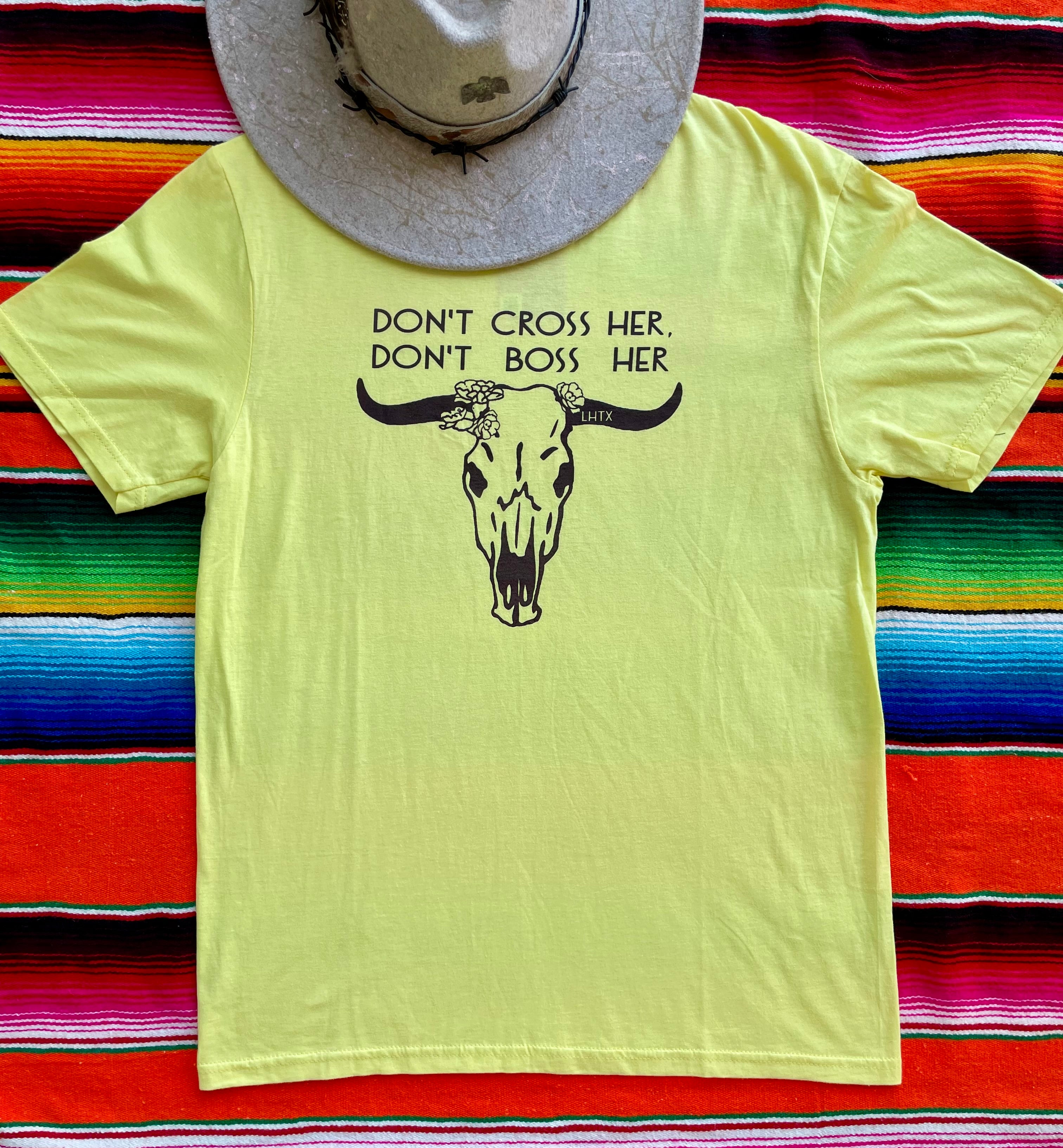 Yellow t-shirt with a bull skull graphic and text on a colorful striped background