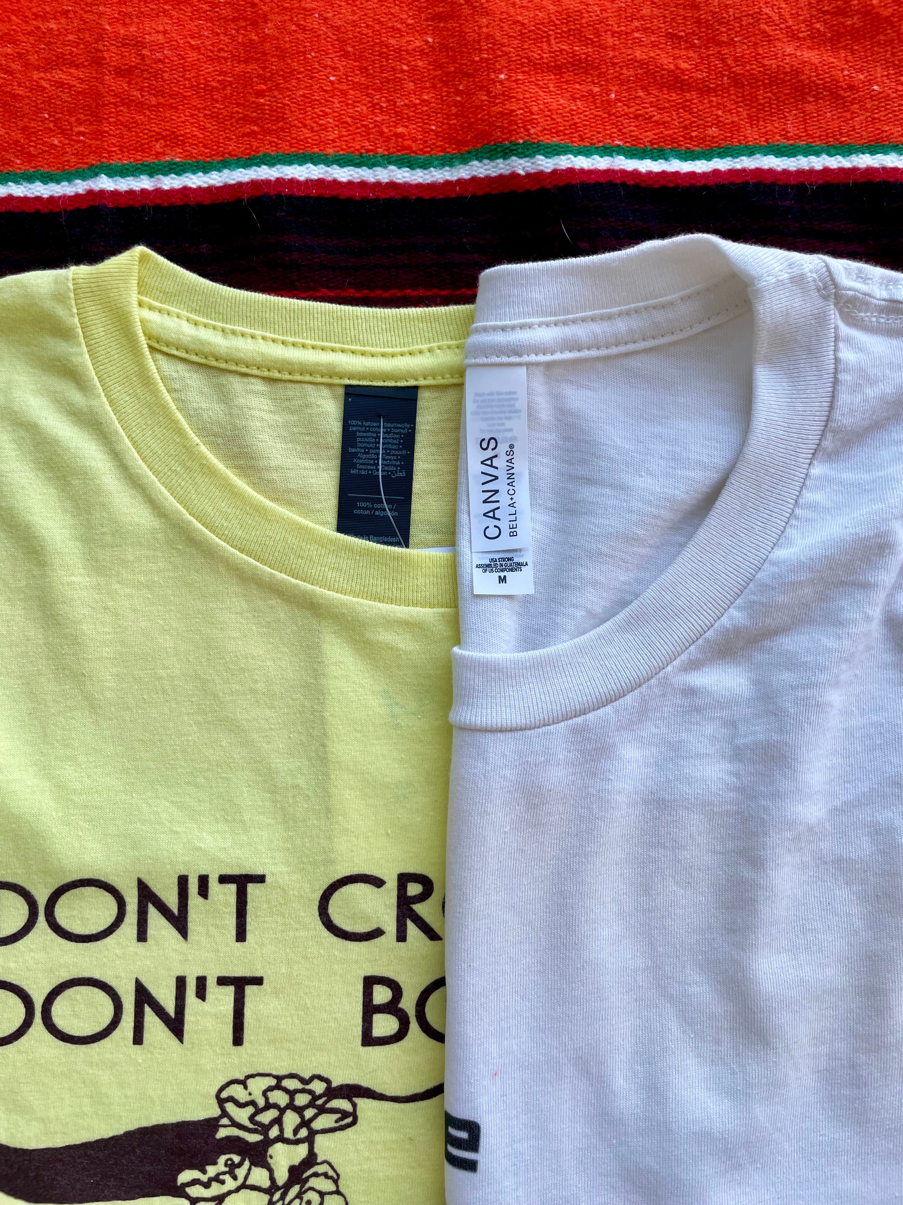 Two t-shirts, one yellow with text and the other white, displayed side by side.