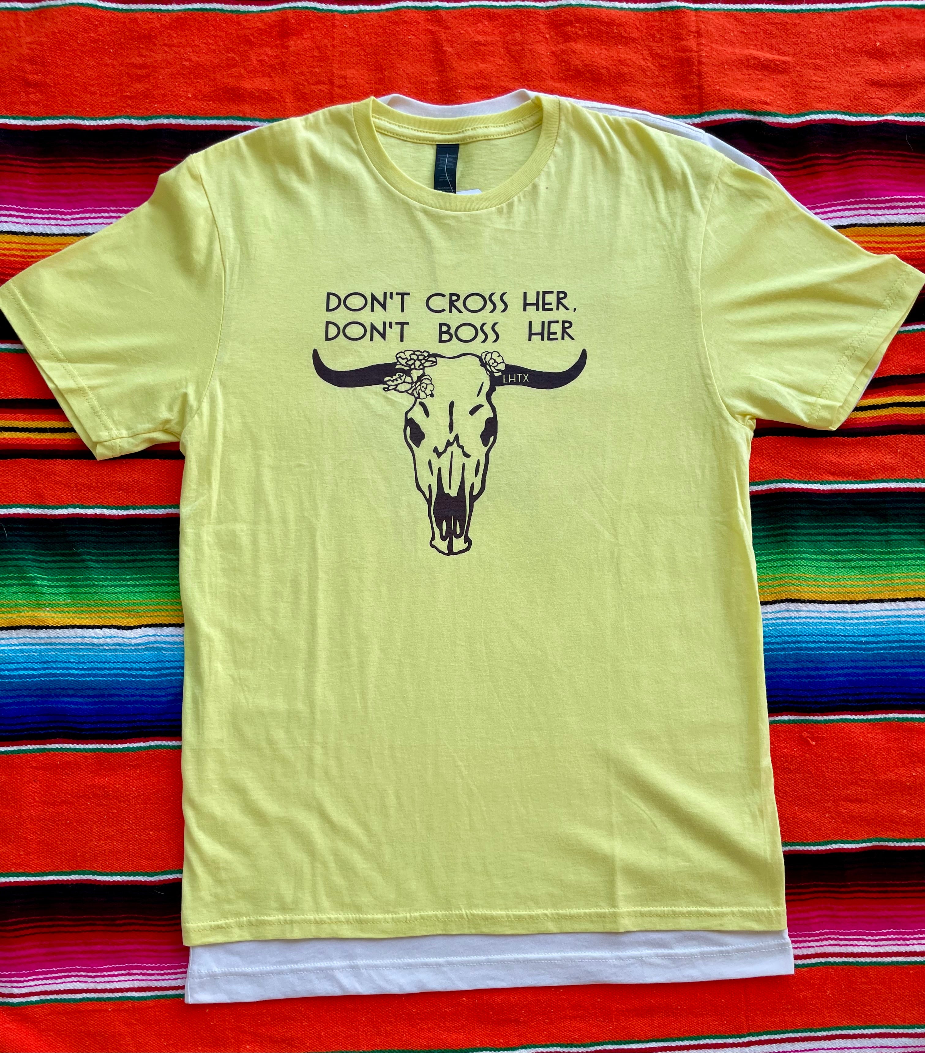 Yellow t-shirt with a bull skull graphic and text on a colorful striped background