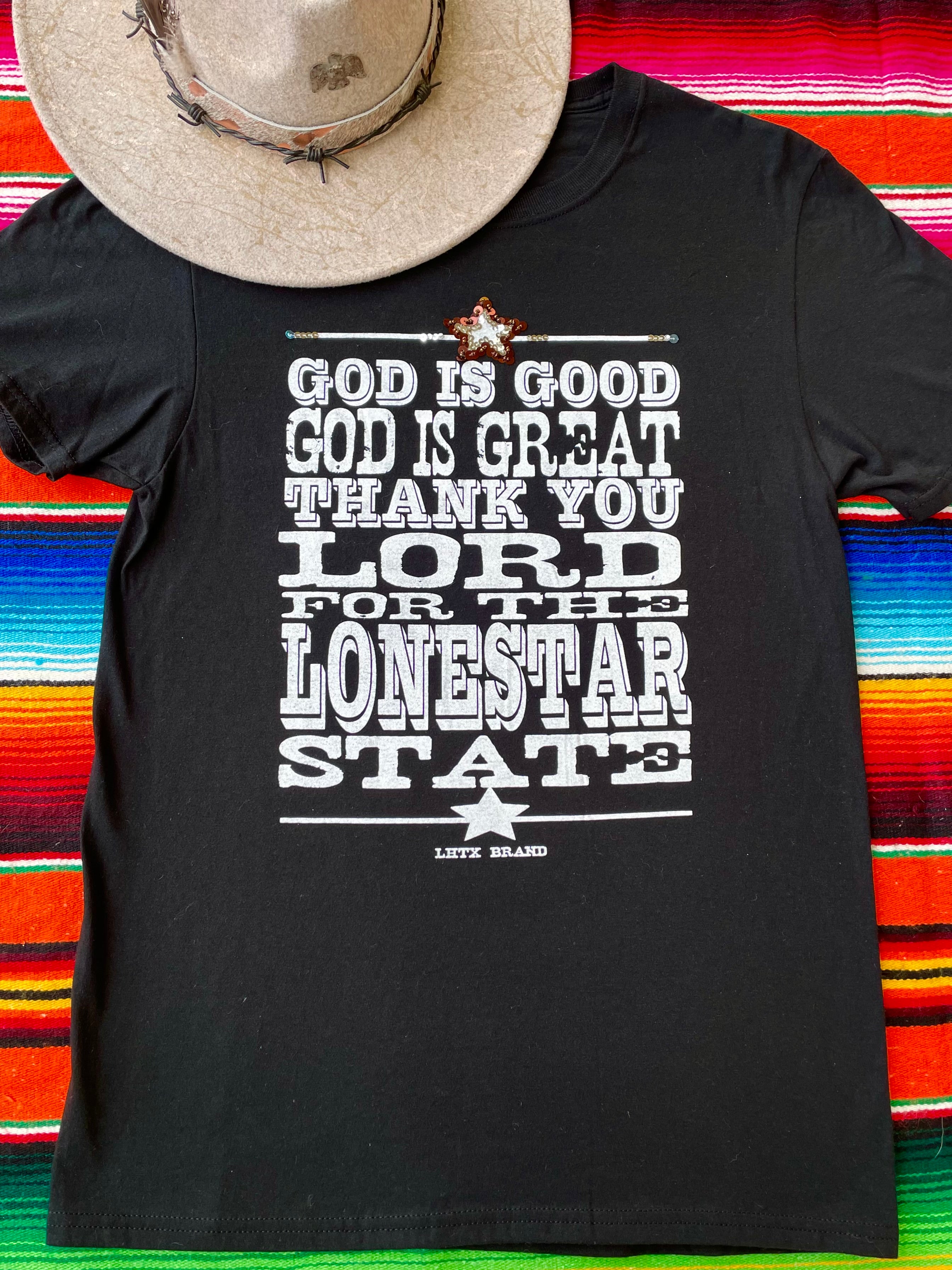 Black t-shirt with white text on a colorful serape background