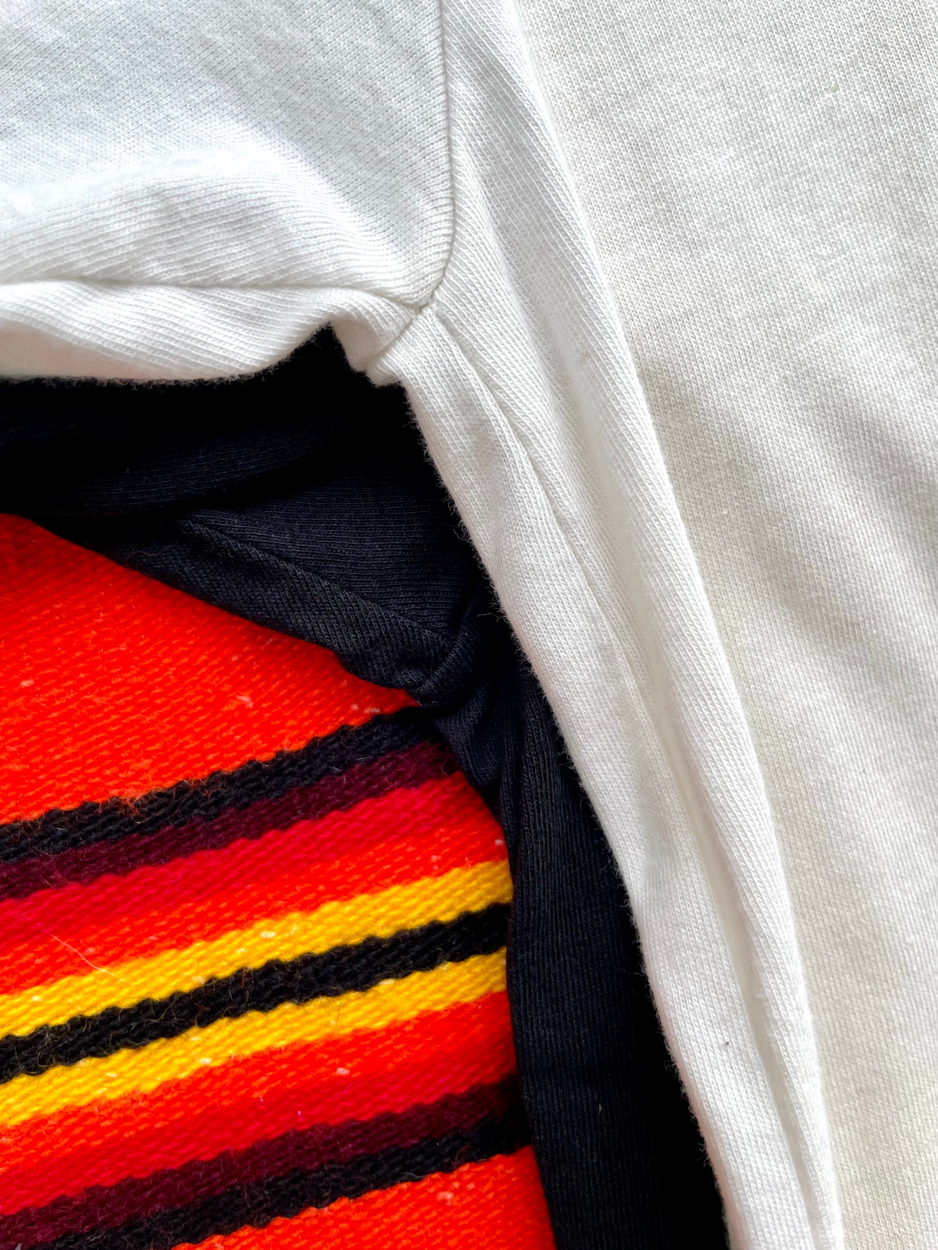 Close-up of a white long-sleeve shirt with a colorful striped fabric underneath.