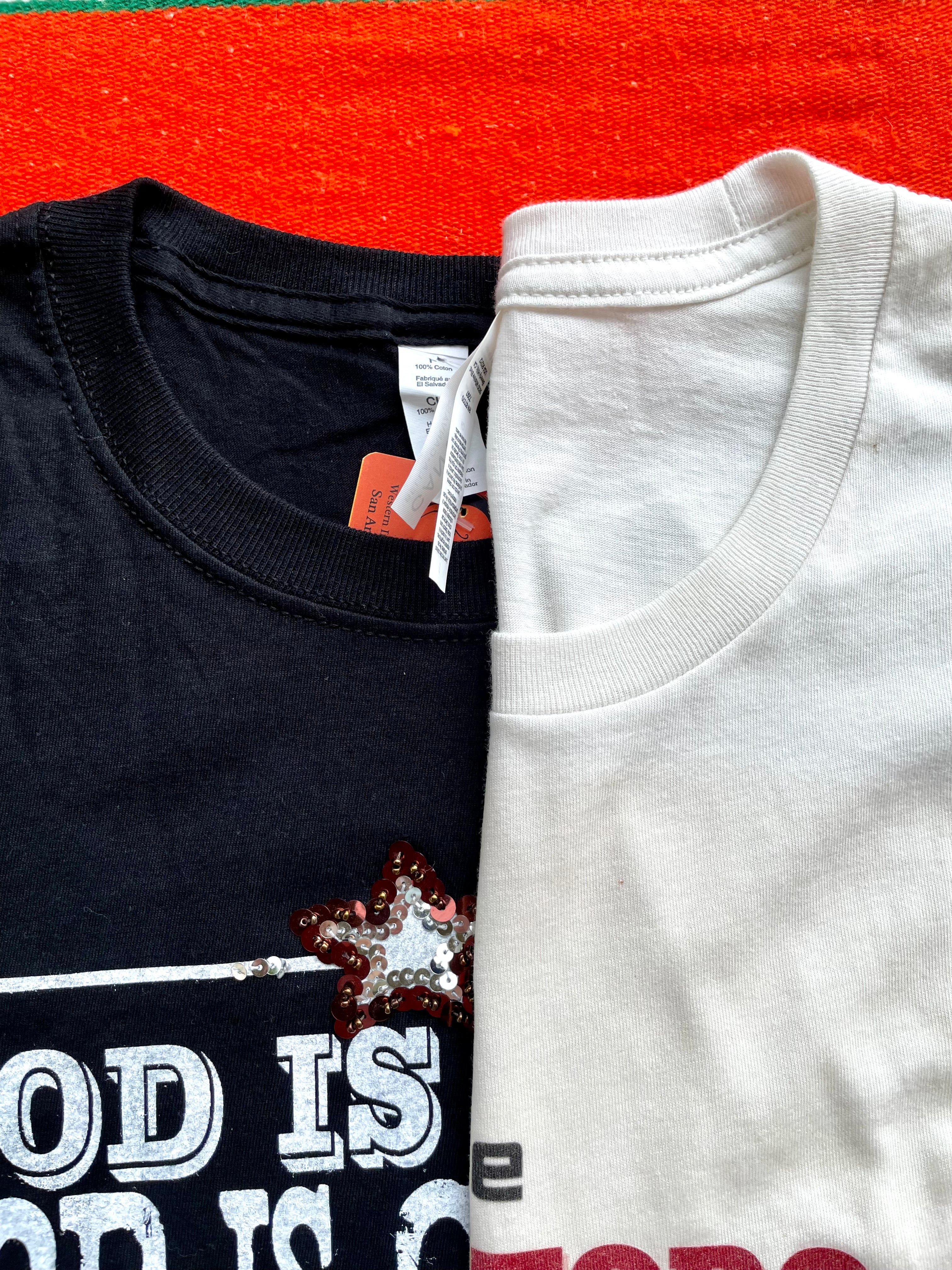 Black and white t-shirts with text and graphics on an orange surface