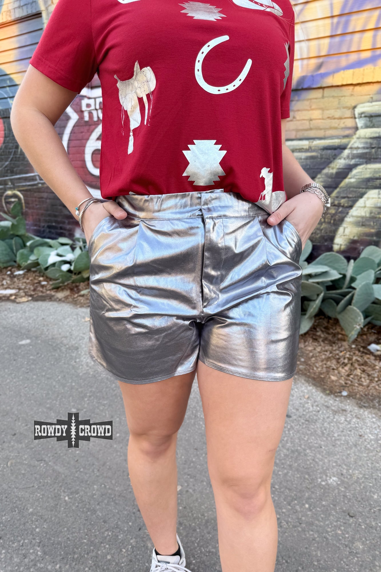 Woman wearing a graphic t-shirt and Rowdy Crowd silver metallic shorts 