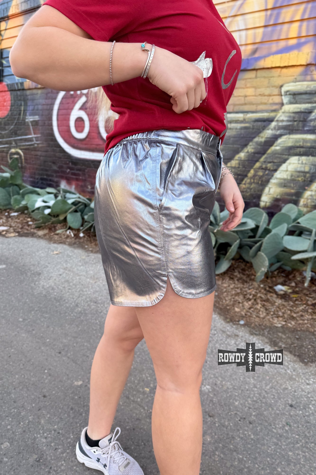 Woman wearing a graphic t-shirt and Rowdy Crowd silver metallic shorts 