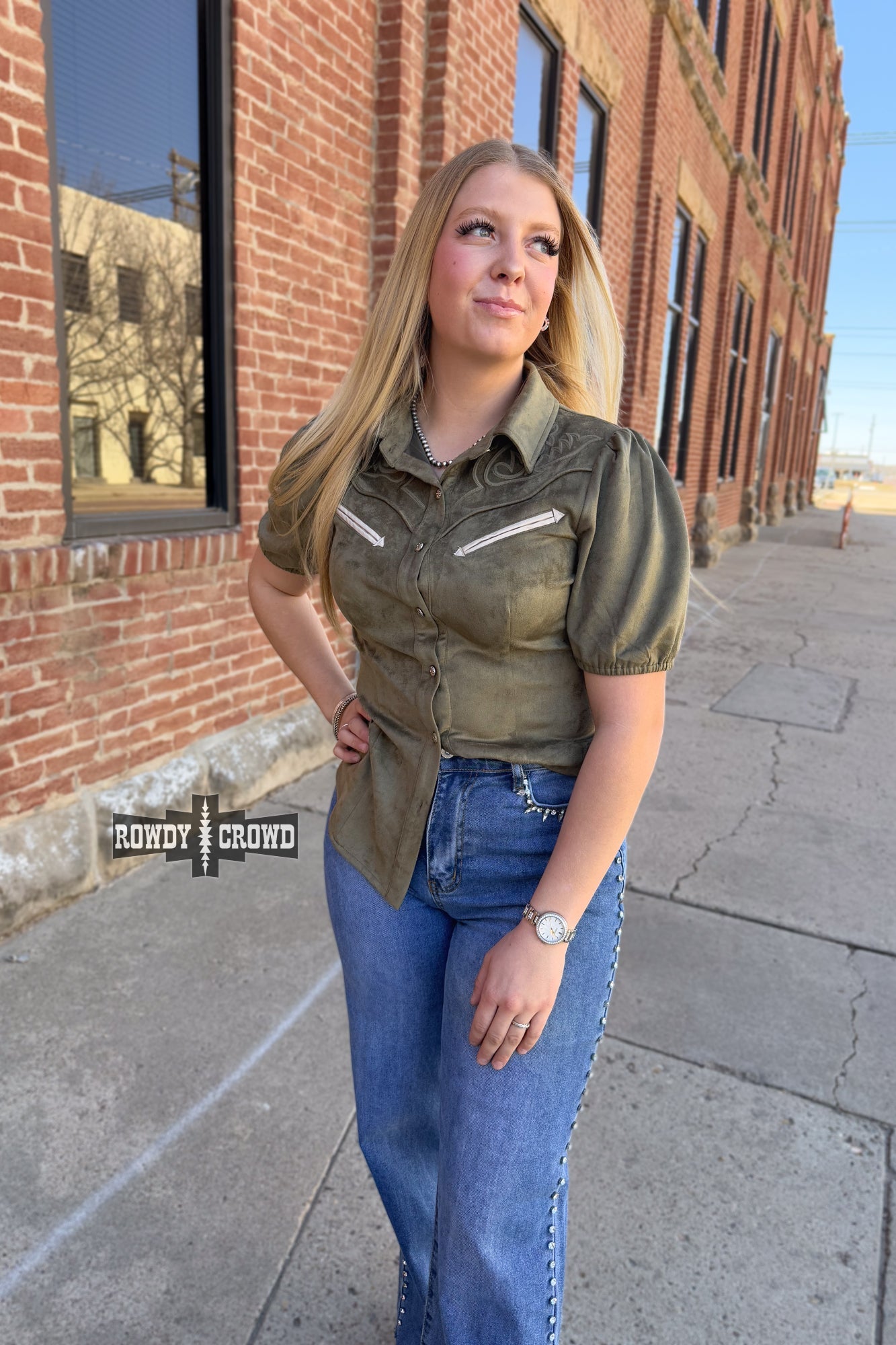Woman in a western style Rowdy Crowd button up green shirt and black pants