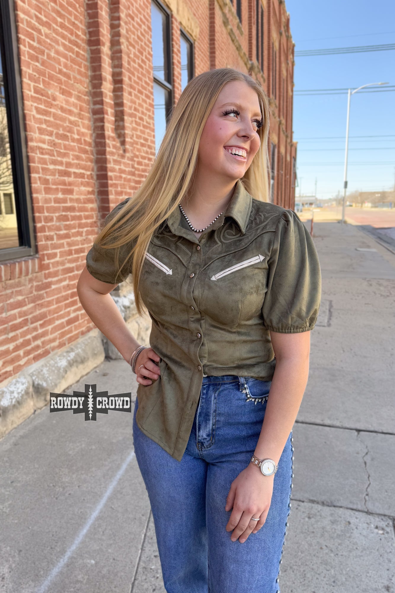 Woman in a western style Rowdy Crowd button up green shirt and black pants