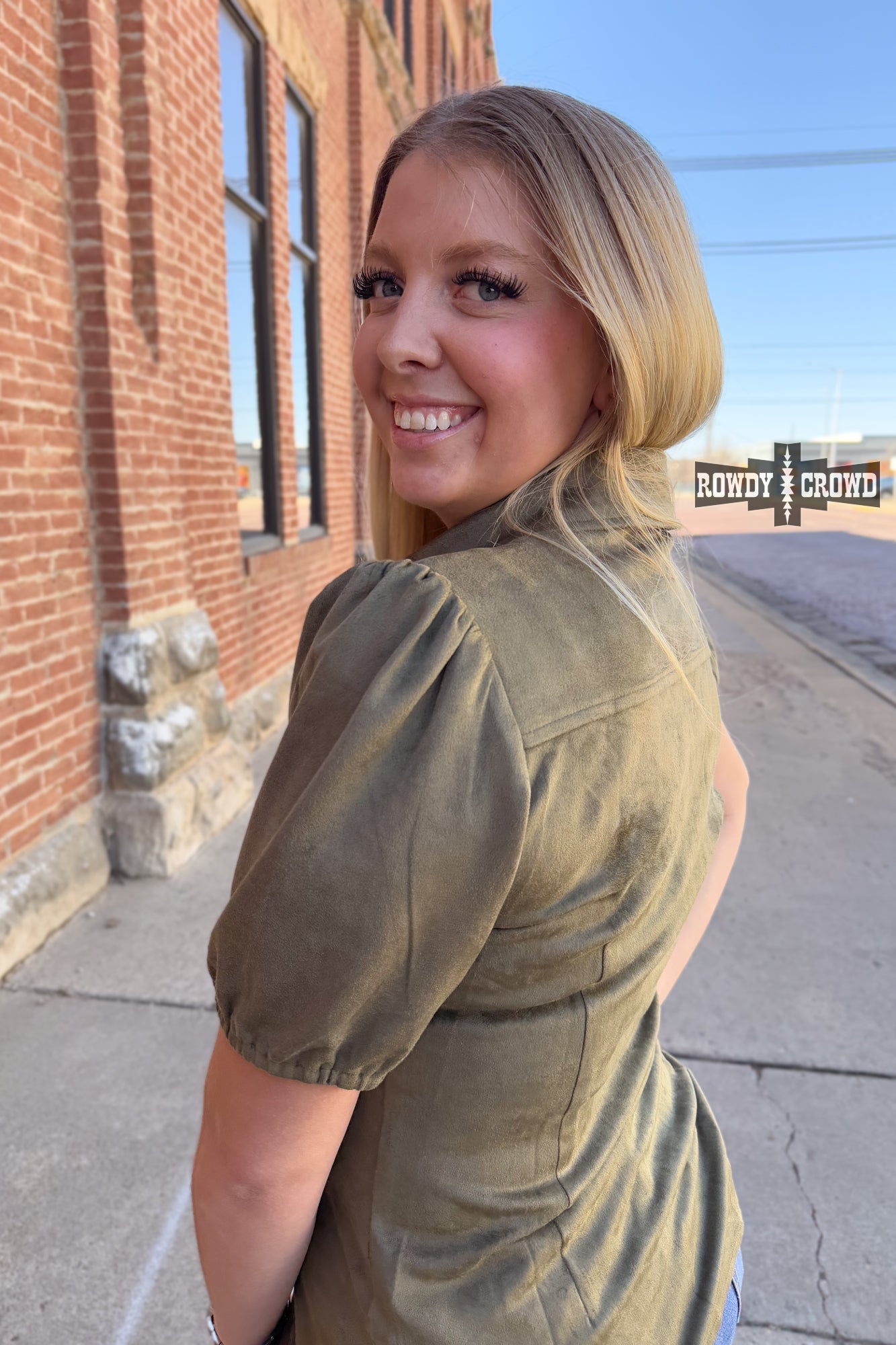 Woman in a western style Rowdy Crowd button up green shirt and black pants