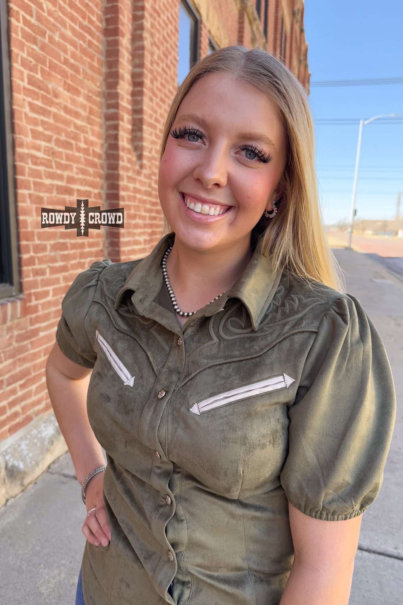 Woman in a western style Rowdy Crowd button up green shirt and black pants