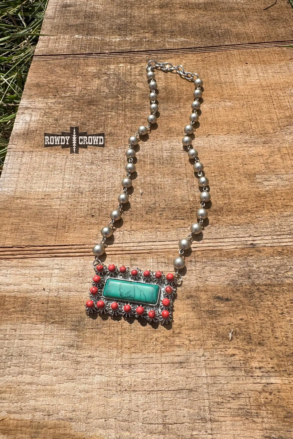 close up of honky tonk necklace silver beads turquoise inspired pendant framed in red accents western cowgirl accessory
