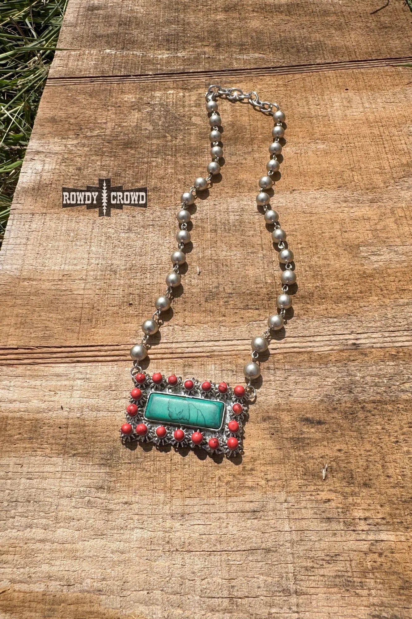 close up of honky tonk necklace silver beads turquoise inspired pendant framed in red accents western cowgirl accessory