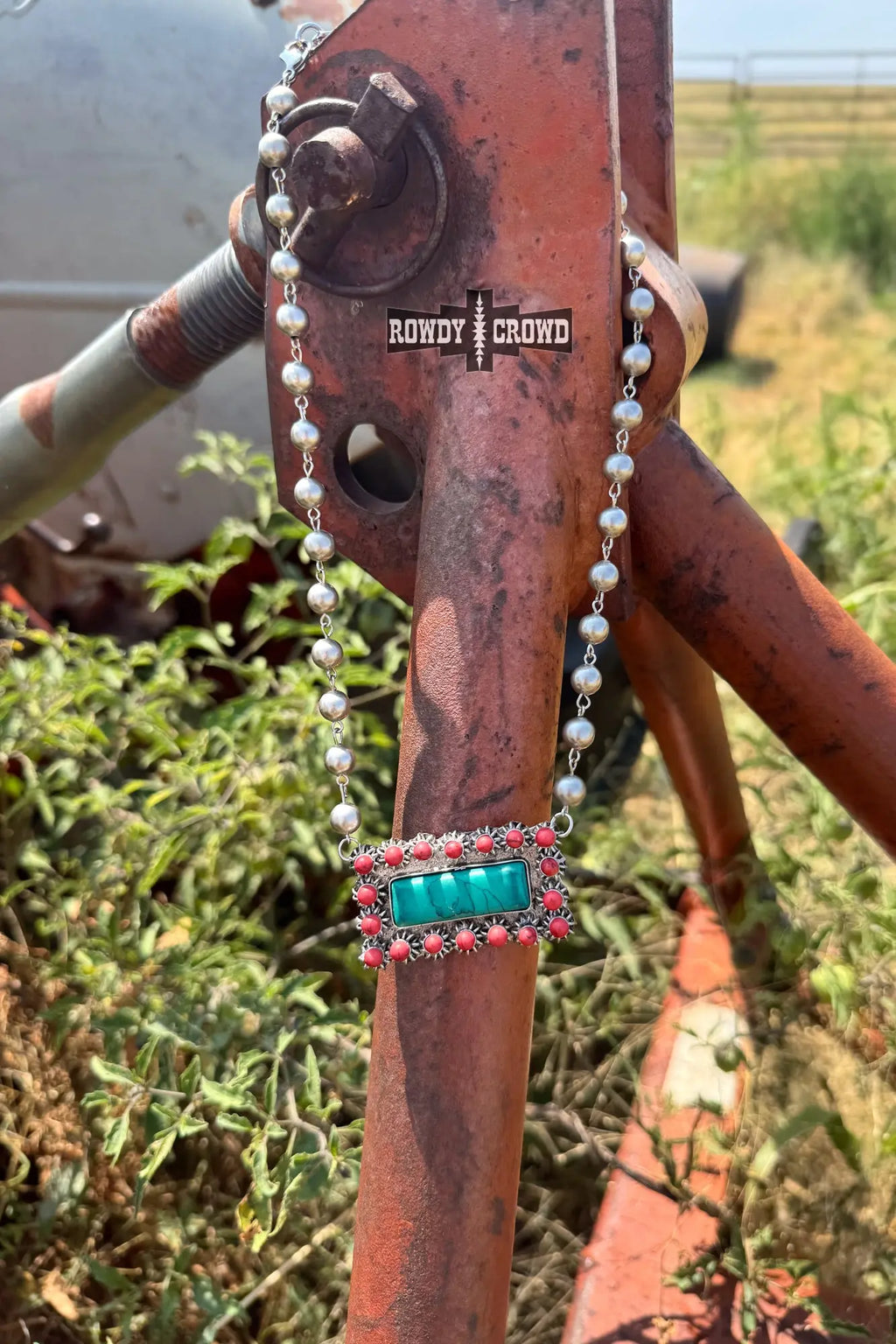 close up of honky tonk necklace silver beads turquoise inspired pendant framed in red accents western cowgirl accessory
