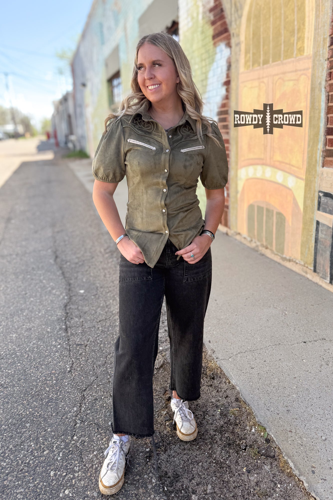 Woman in a western style Rowdy Crowd button up green shirt and black pants