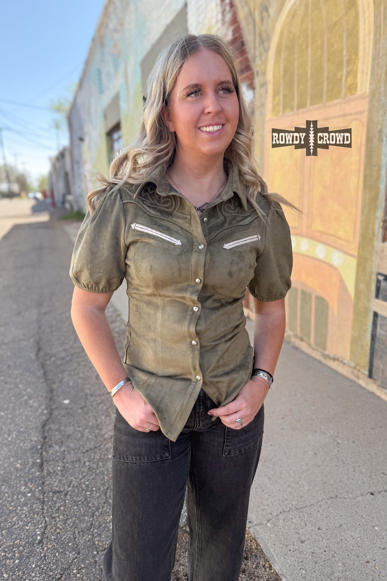 Woman in a western style Rowdy Crowd button up green shirt and black pants