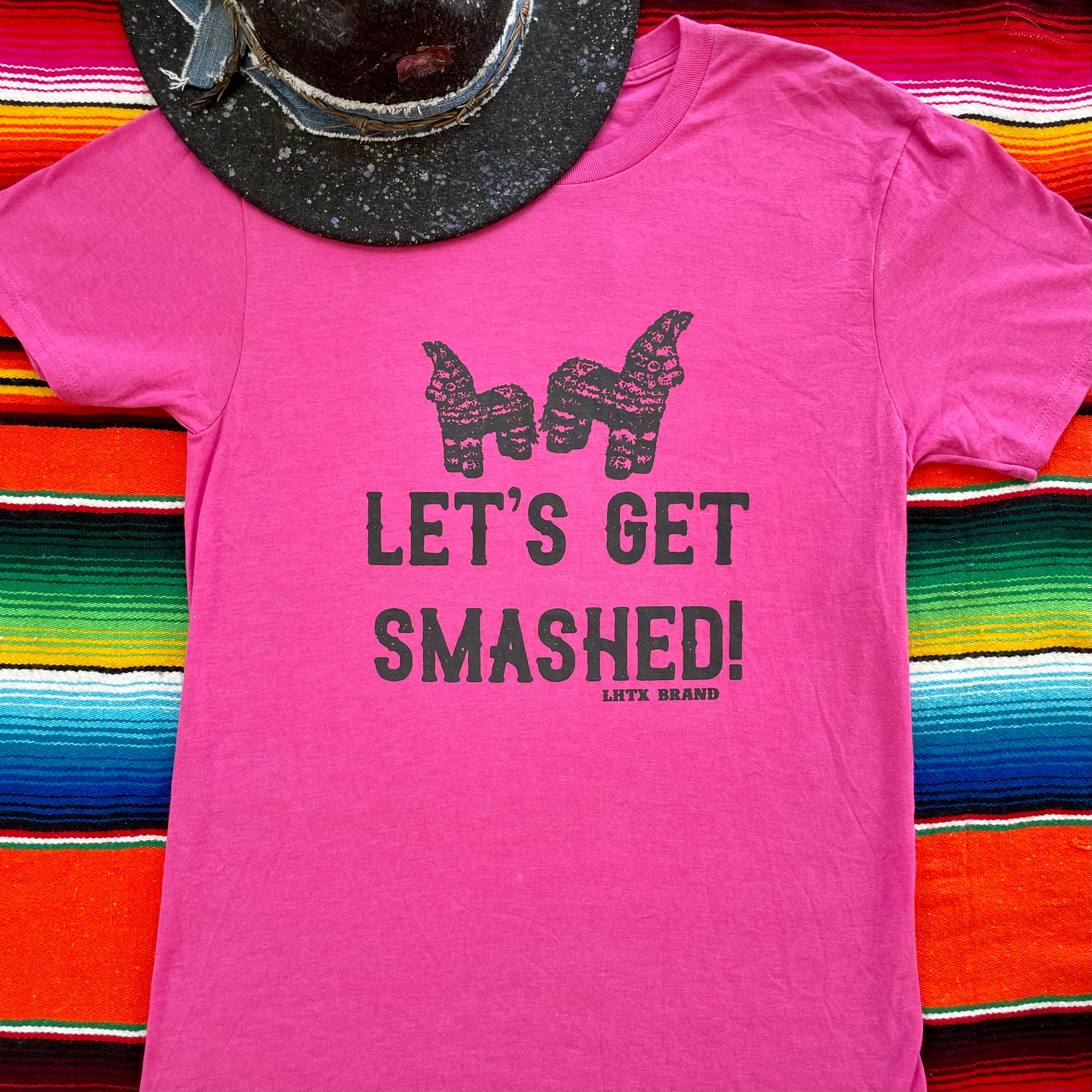 Pink t-shirt with 'Let's Get Smashed!' text and alpaca graphic on a colorful striped background
