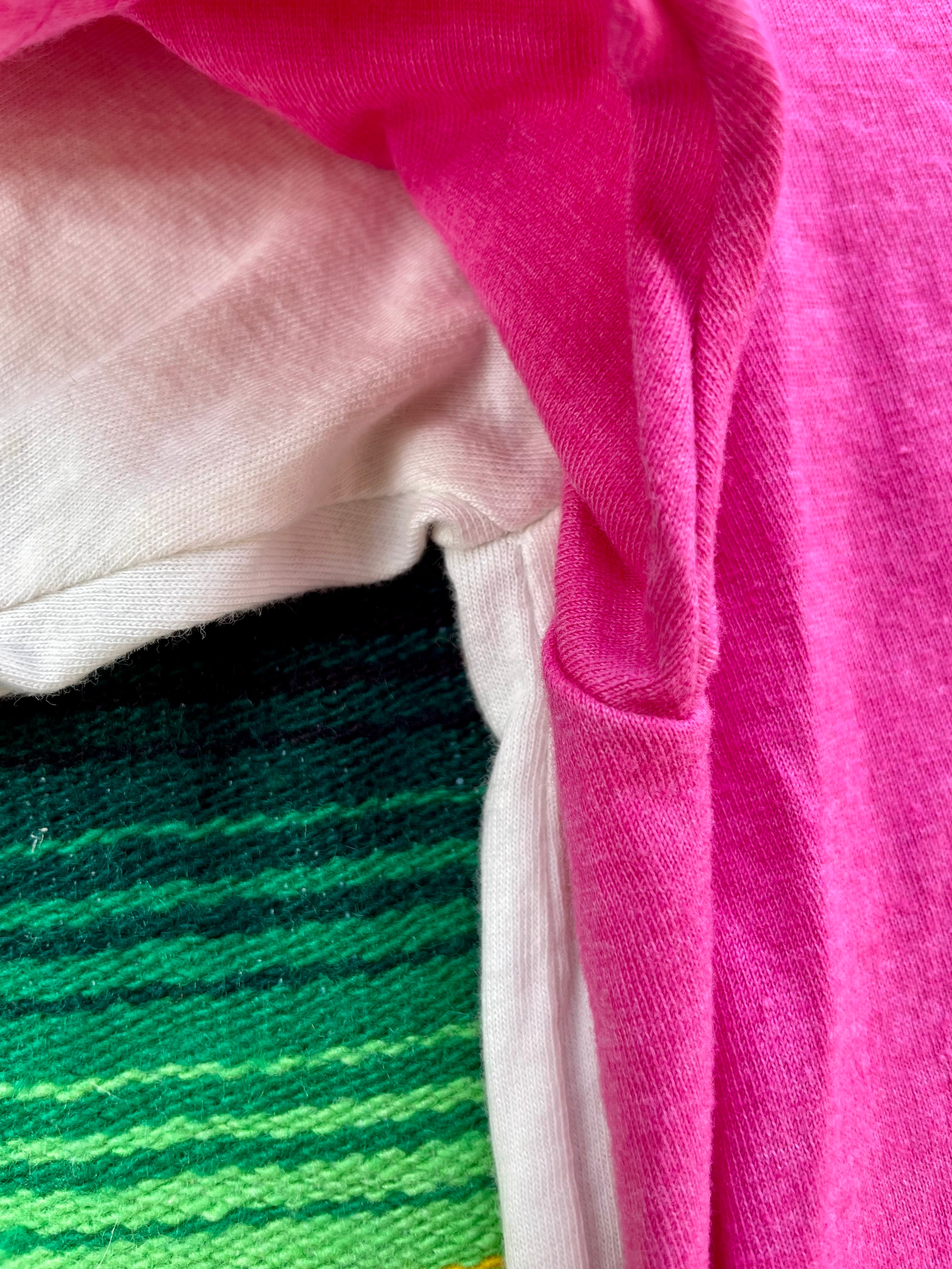 Close-up of a pink fabric with a green and blue striped pattern underneath.