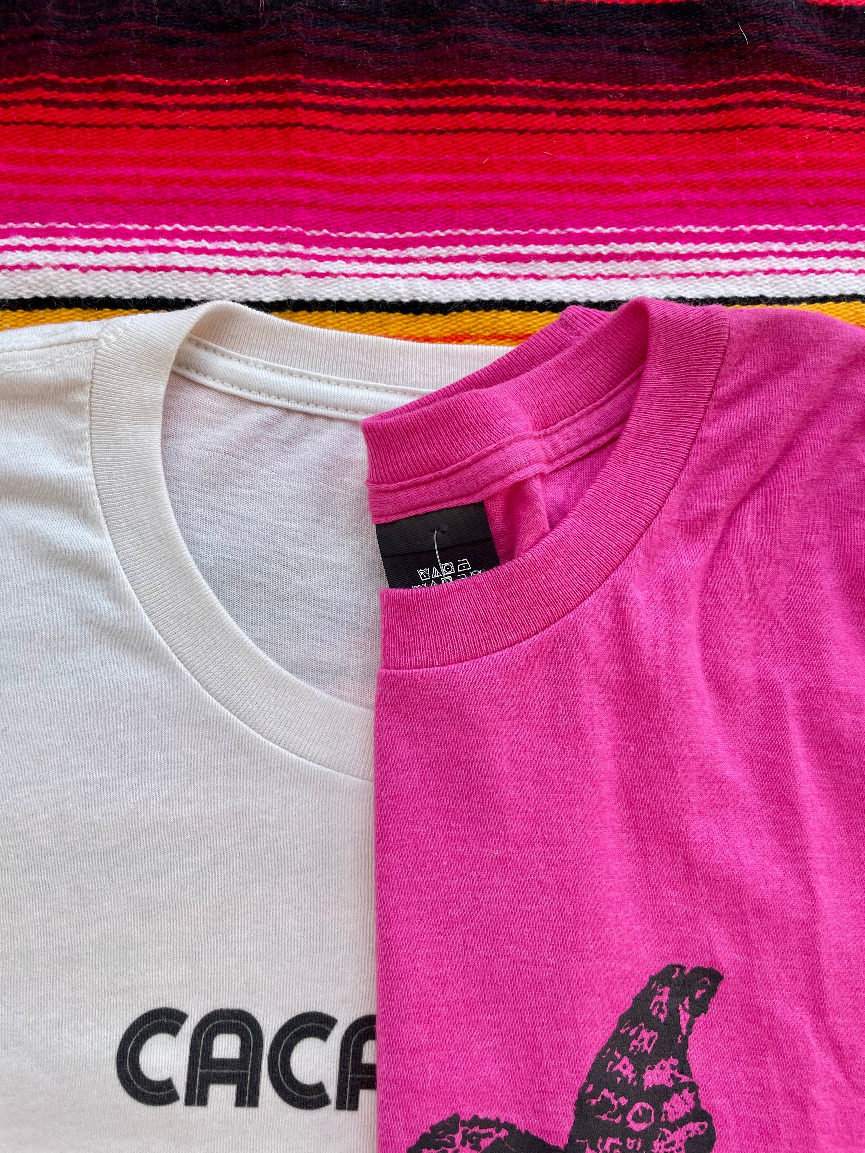 Two t-shirts, one white and one pink, with a brand logo on a colorful striped background.