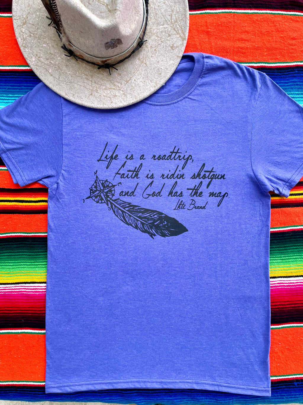 Blue t-shirt with text and feather graphic on a colorful striped background