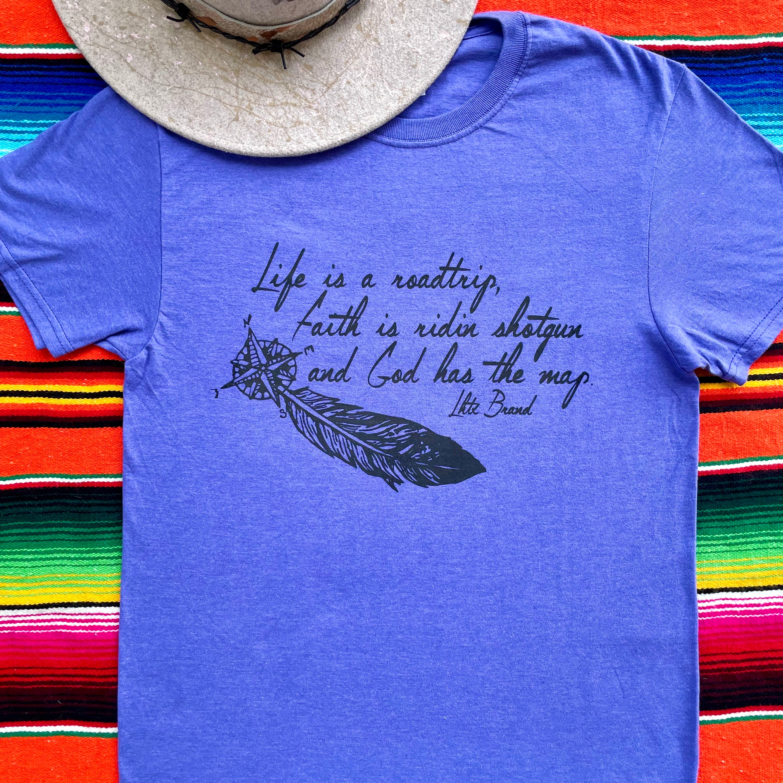 Blue t-shirt with a feather graphic and text on a colorful striped background