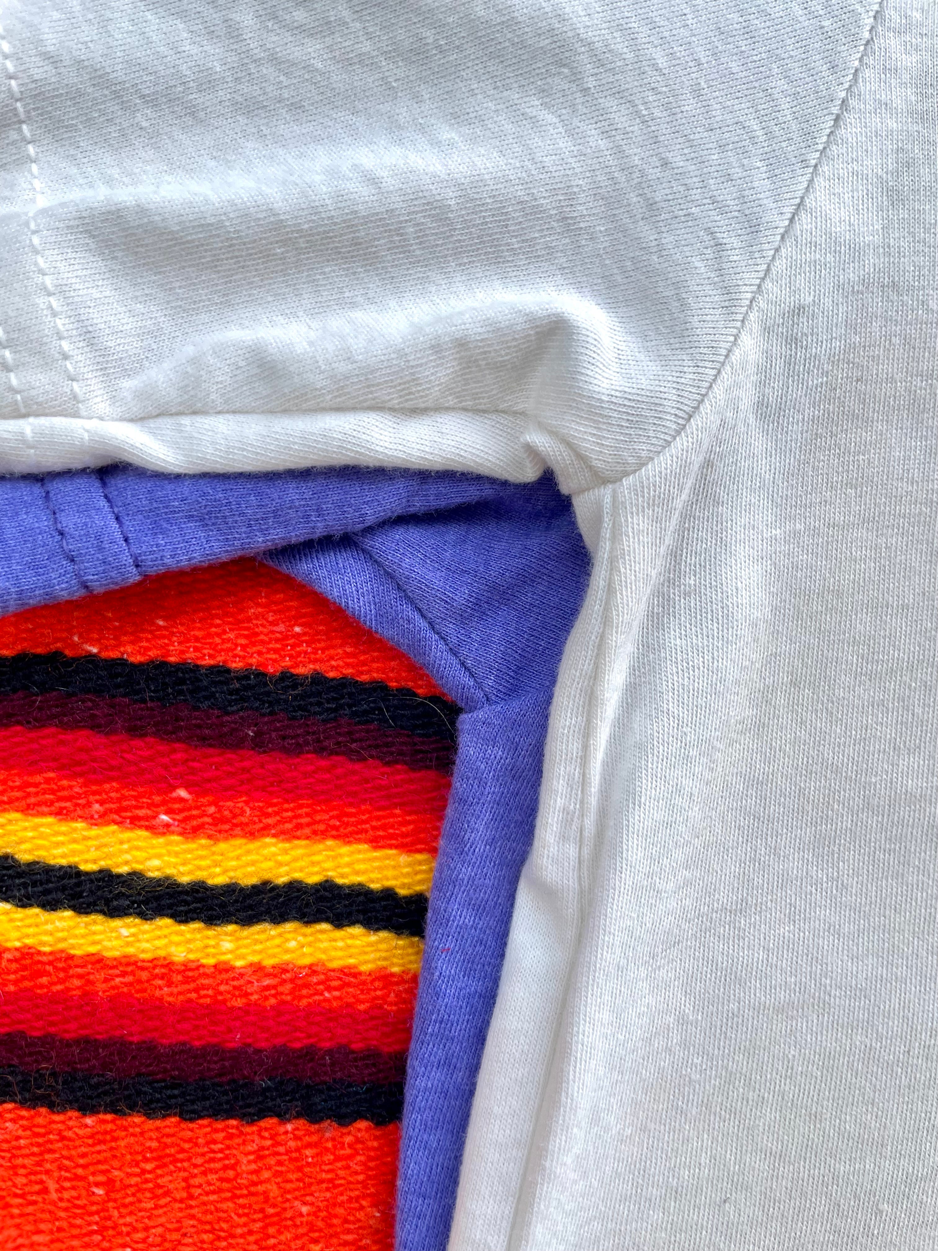 Blue t-shirt with text and feather graphic on a colorful striped background