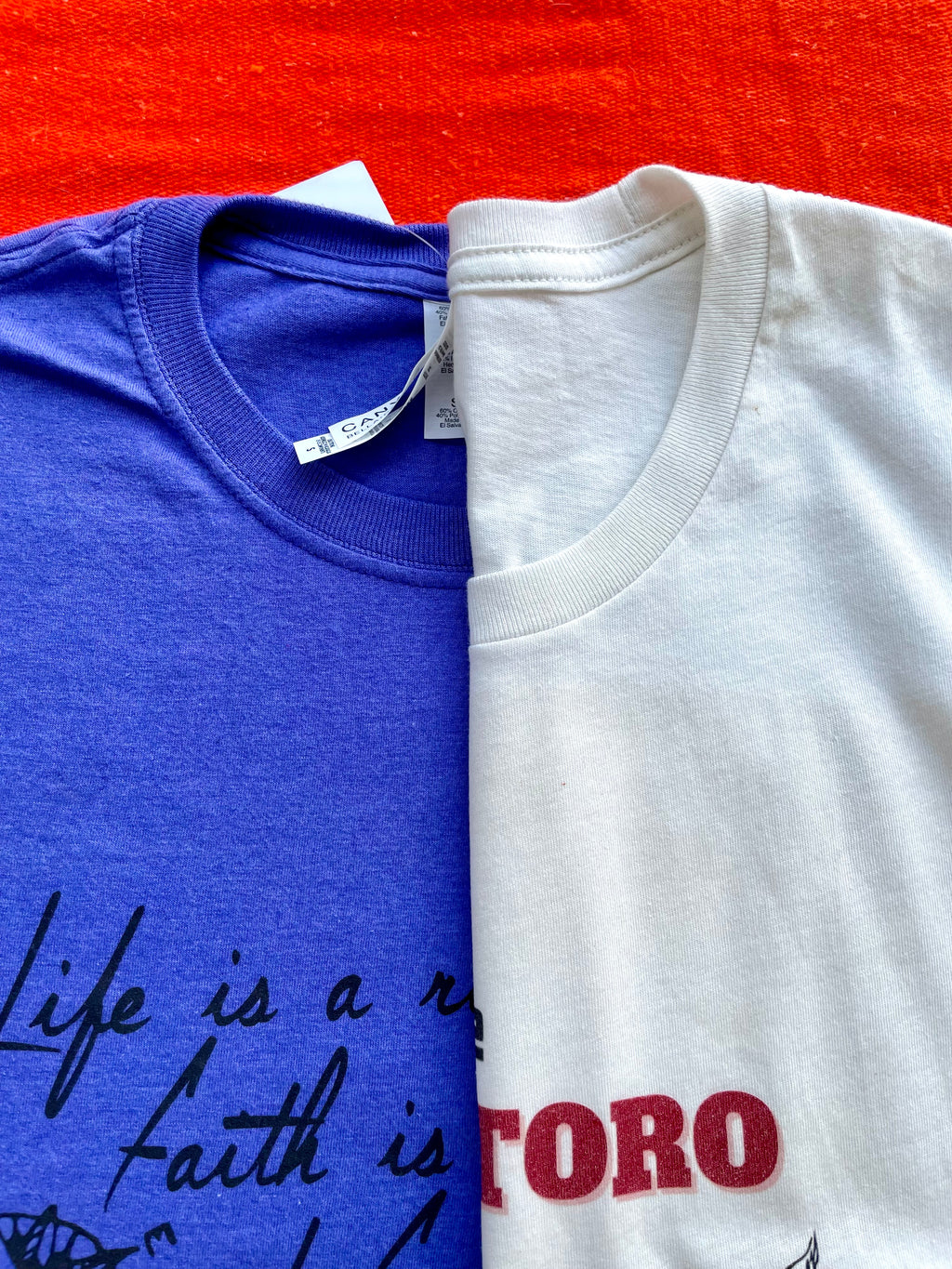 Blue t-shirt with text and feather graphic on a colorful striped background