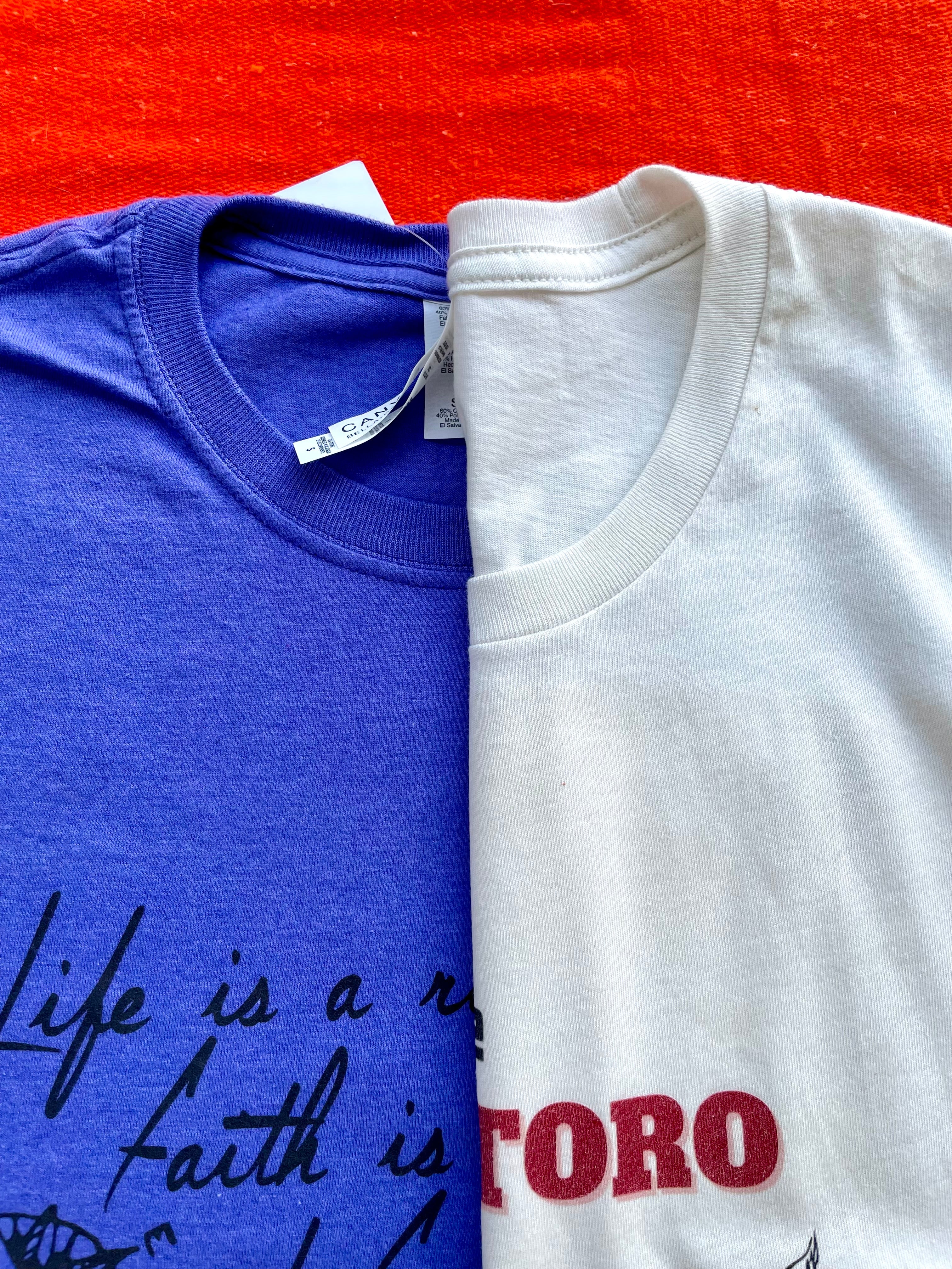 Blue t-shirt with text and feather graphic on a colorful striped background