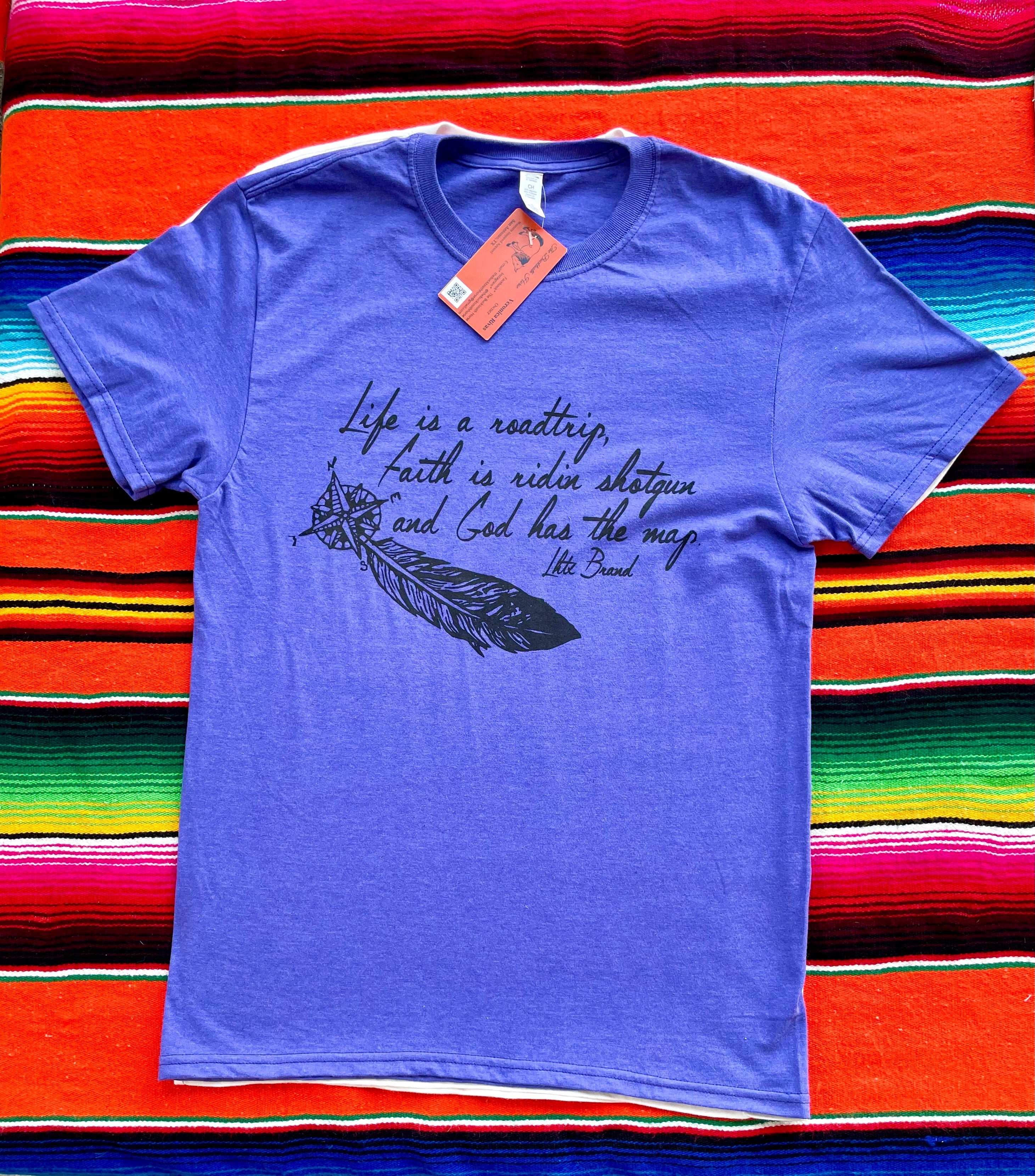 Blue t-shirt with text and feather graphic on a colorful striped background