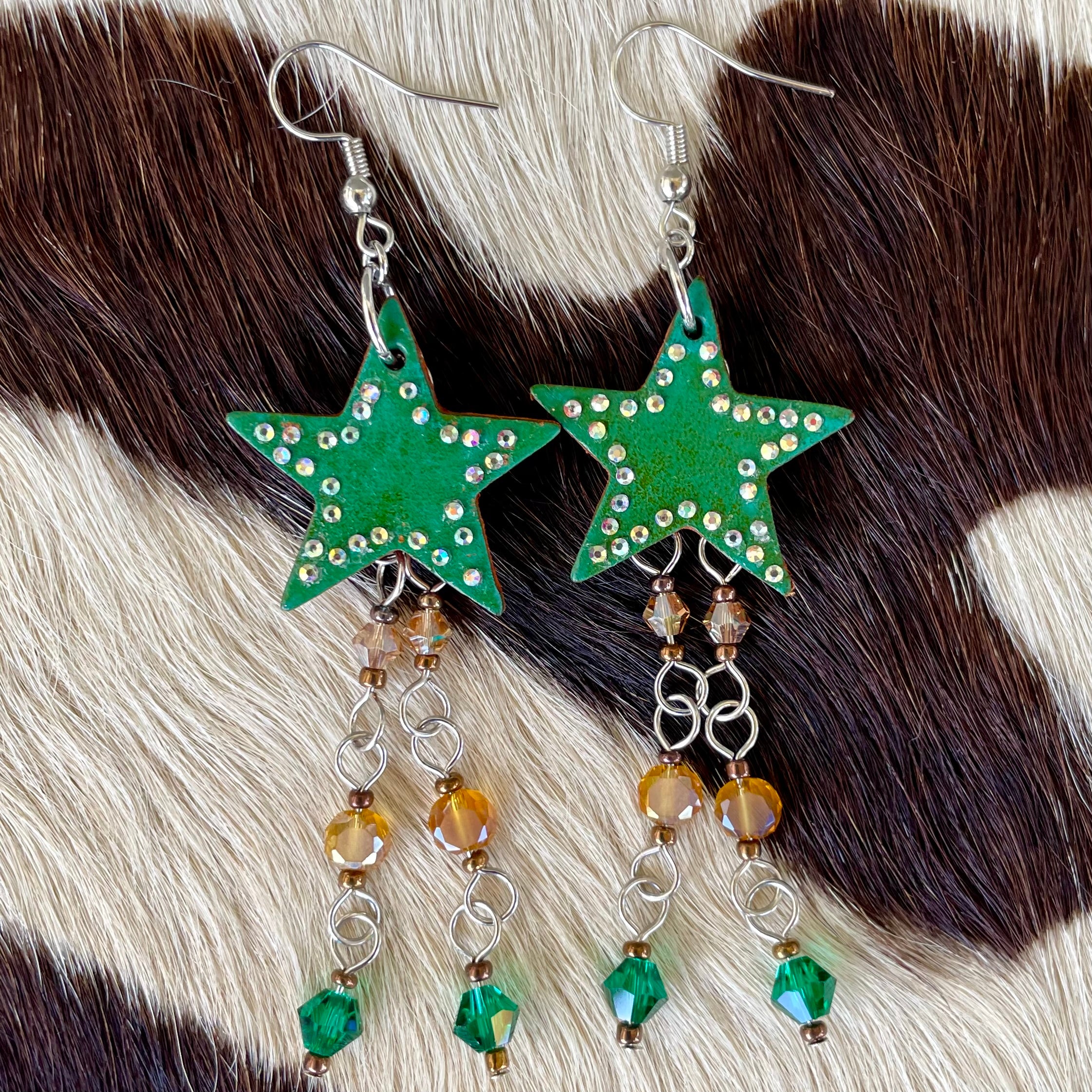 Green star earrings with bead accents on a fur background