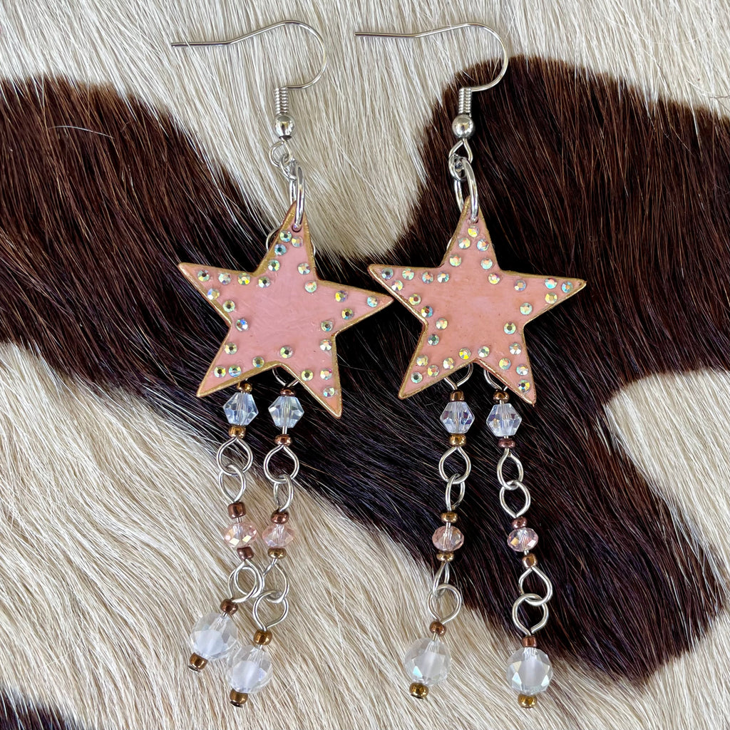 Star-shaped earrings with pink color and bead details on a fur background