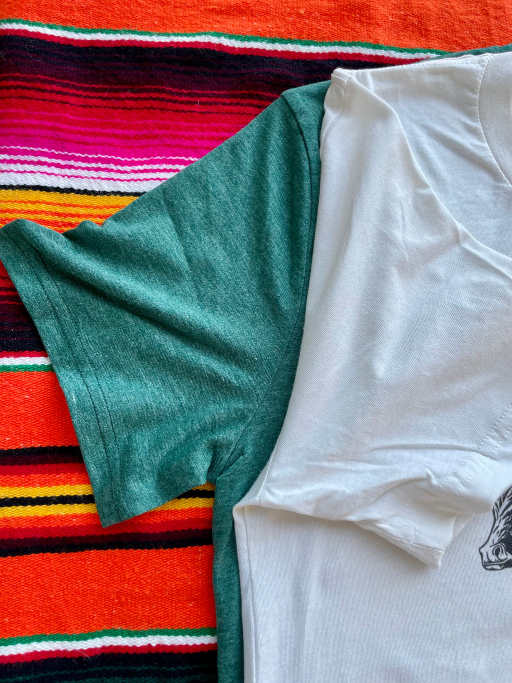 Green and white t-shirts on a colorful striped fabric background