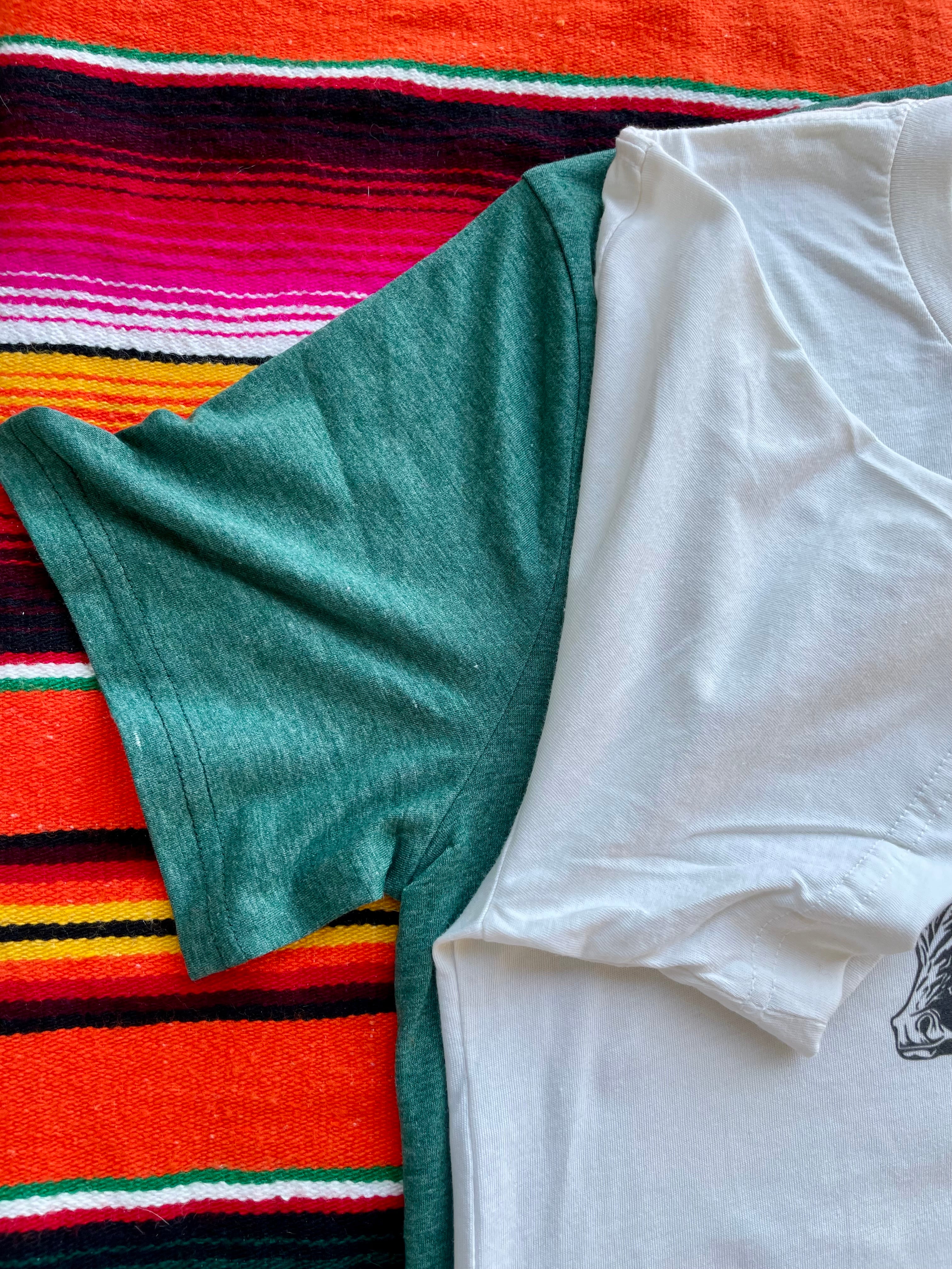 Green and white t-shirts on a colorful striped fabric background