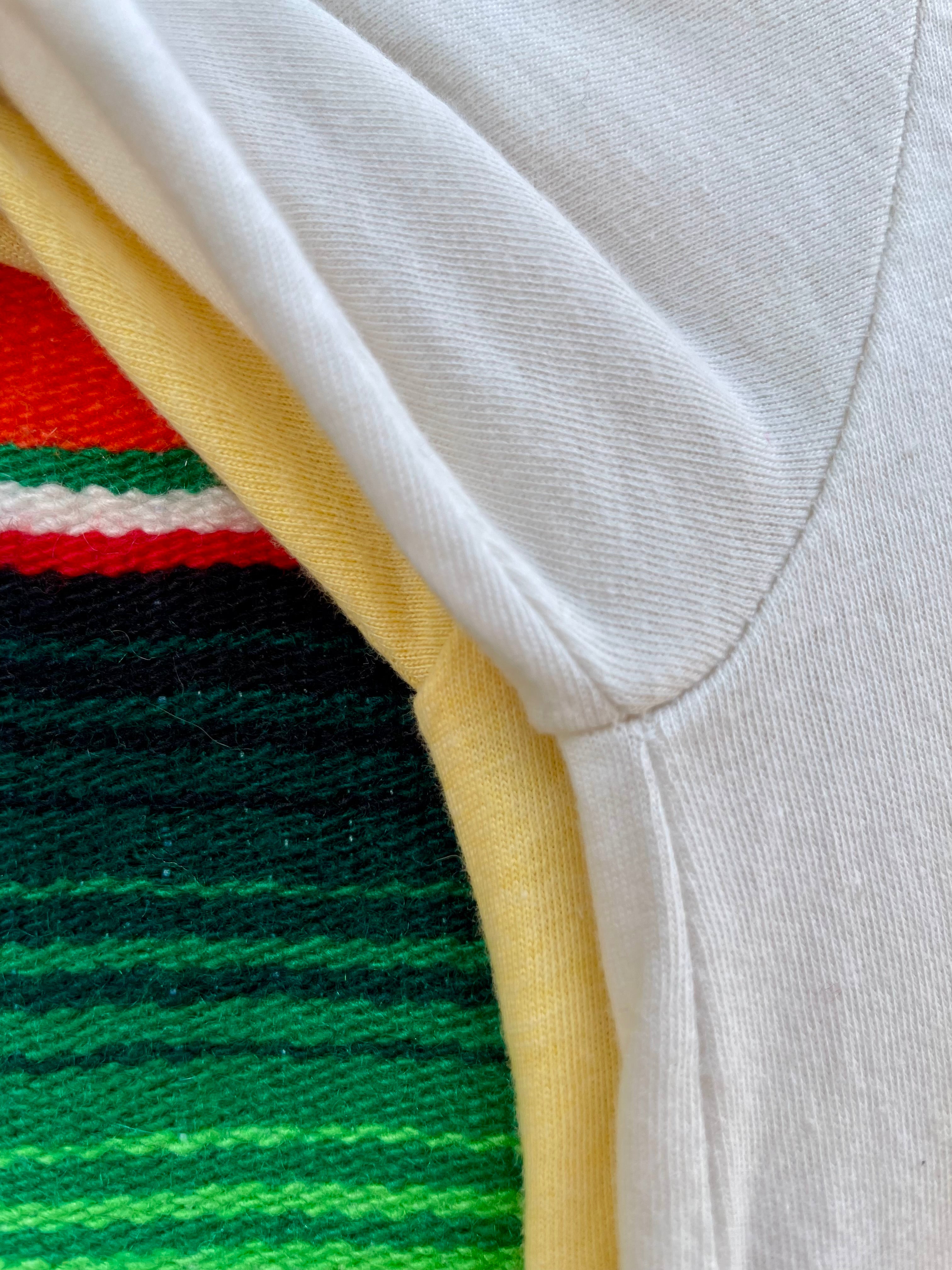 Yellow t-shirt with a graphic design of a woman in a hat and skirt, cactus, and sun on a colorful striped background.