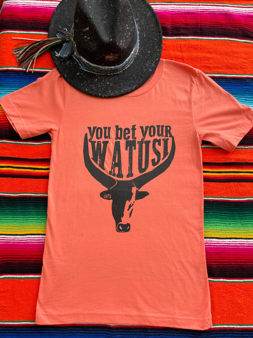 Tangerine cowgirl graphic t-shirt with "You Bet Your Watusi" slogan and illustrated by LHTX with a hand drawn Watusi bullhead western fashion apparel by the Bucktooth Horse