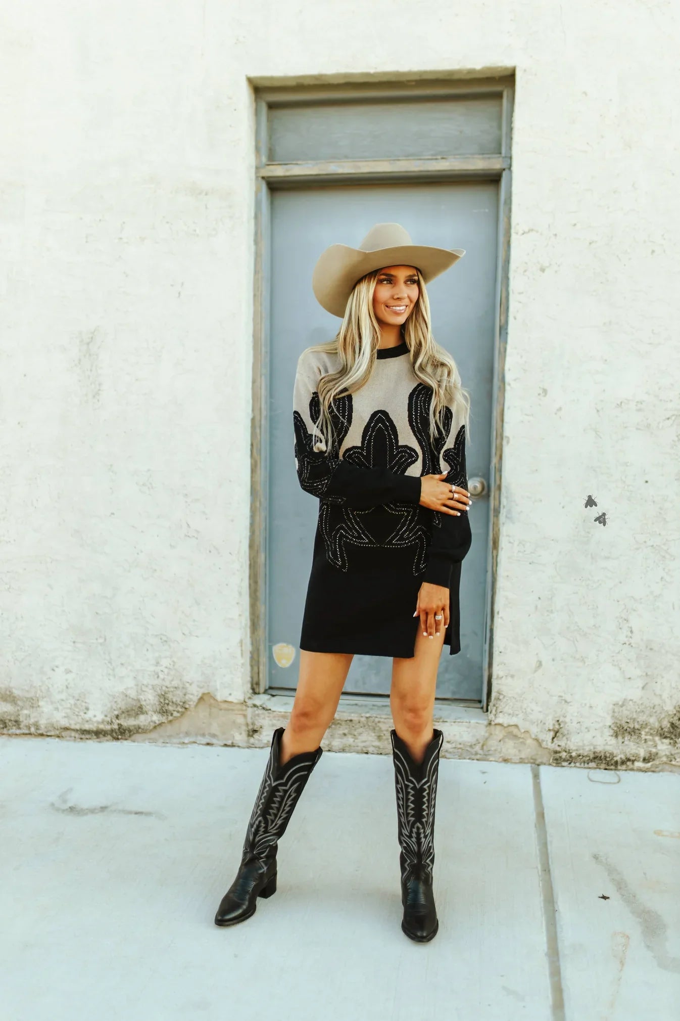 Woman wearing a black and beige patterned western style boot print dress with a cowboy hat